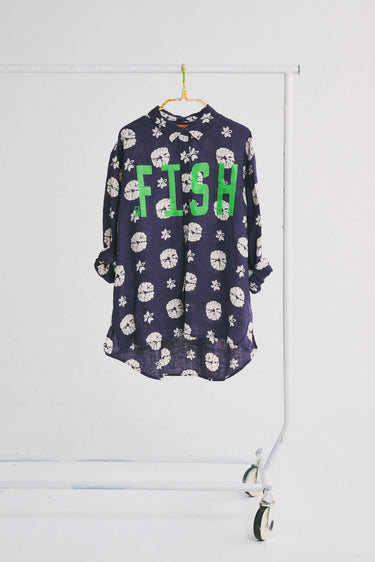 Navy seashell button down with green FISH text on a white rack