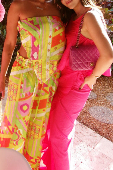 Two women in colorful outfits with one holding a pink handbag.