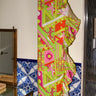 Colorful patterned ruffle power pareo skirt hanging against a wall with a tiled base.