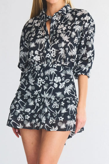 Woman wearing a black and white palm tree and floral mini skirt and button down on a white background