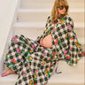 Pregnant person sitting on a staircase wearing a floral and checkered button down shirt and bubble pants.