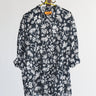 Black palm tree patterned button down shirt on a hanger against a white background