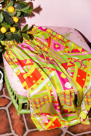 Colorful patterned pants on a green ottoman with a pink cushion.