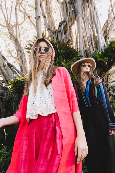 Two women in colorful outfits standing outdoors with trees in the background
