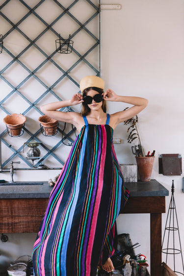 Woman in a colorful striped dress standing in a kitchen.