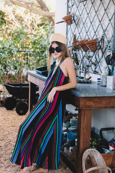 Woman in a colorful striped dress and sunglasses standing in an outdoor setting.