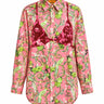 A pink long-sleeve button-up shirt with a green and beige botanical print, featuring a dark red bikini embroidered on the front, displayed on a solid white background.