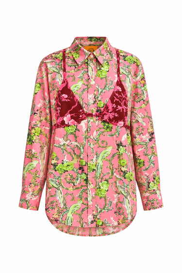 A pink long-sleeve button-up shirt with a green and beige botanical print, featuring a dark red bikini embroidered on the front, displayed on a solid white background.