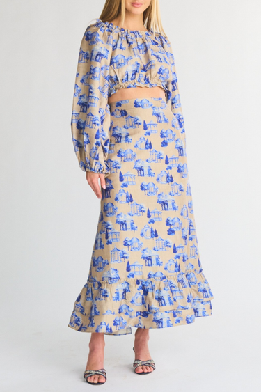 Woman wearing a blue and beige patterned long sleeve cropped top and cinch midi skirt on a white background
