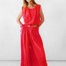 A woman modeling a bright red sleeveless top with wide-leg bubble-style pants and eyelet embroidery, standing against a plain white studio background.