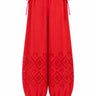Bright red bubble-style pants with drawstring waist, elastic cuffs, and eyelet cutout eyelet details on the lower legs, shown against a plain white background.