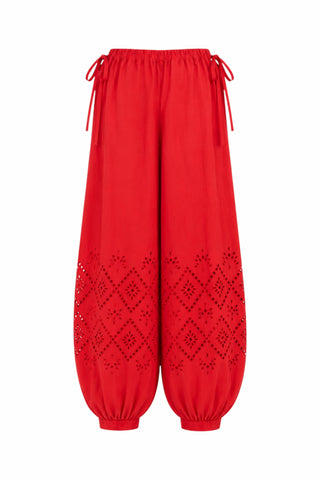 Bright red bubble-style pants with drawstring waist, elastic cuffs, and eyelet cutout eyelet details on the lower legs, shown against a plain white background.