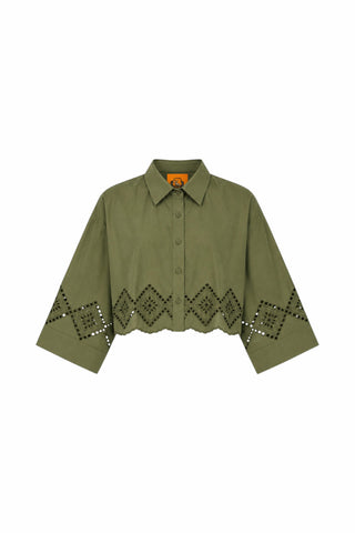 An olive green cropped button-up shirt with a pointed collar and a geometric diamond pattern of cutout eyelet details along the lower front and sleeves, displayed on a solid white background.